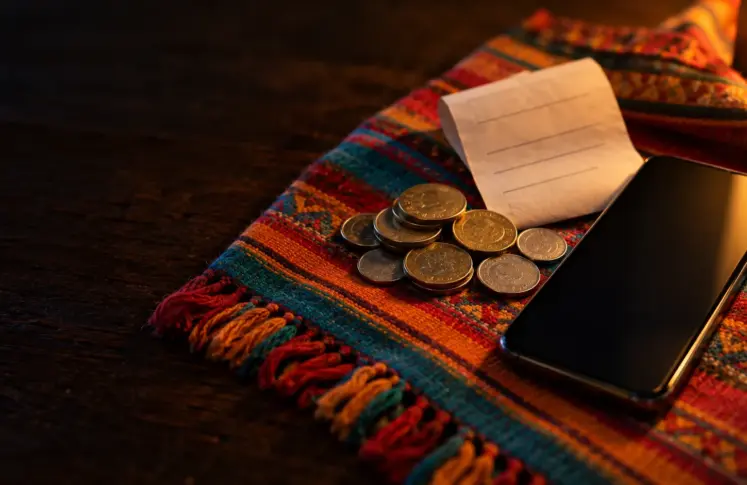 SafetyPay casinos header: coins, a paper receipt and a smartphone on a woven Andean textile