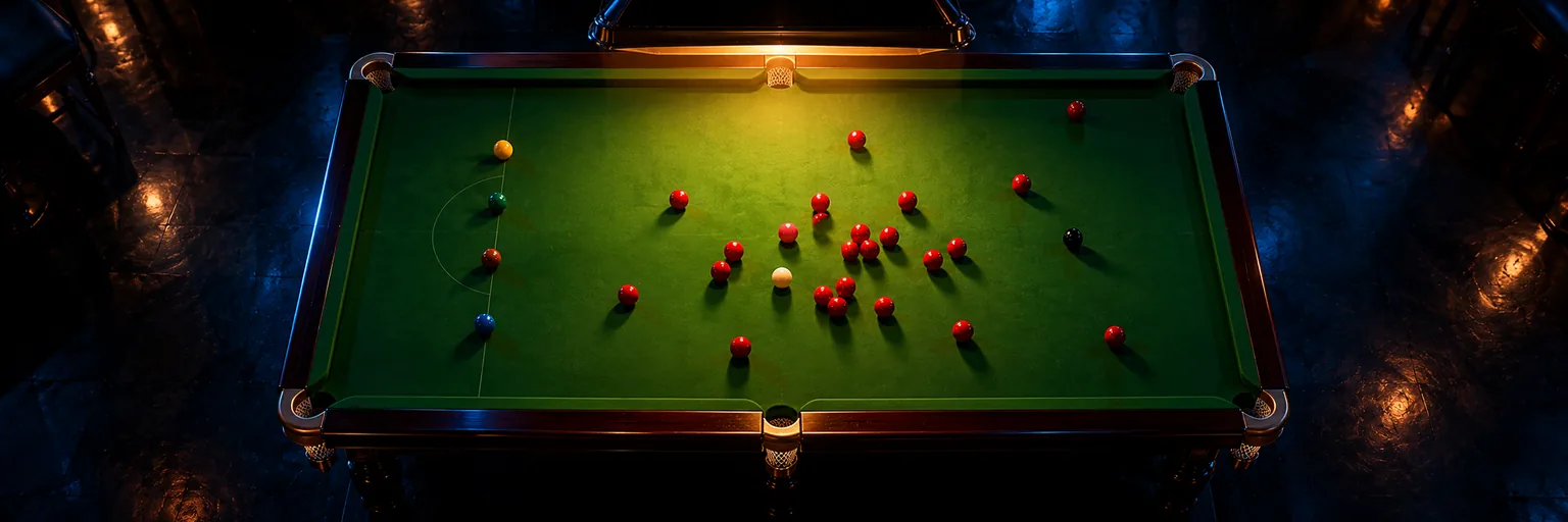 Overhead view of a snooker table with the reds broken across the baize